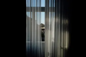 A baby nursery with white curtains on the window